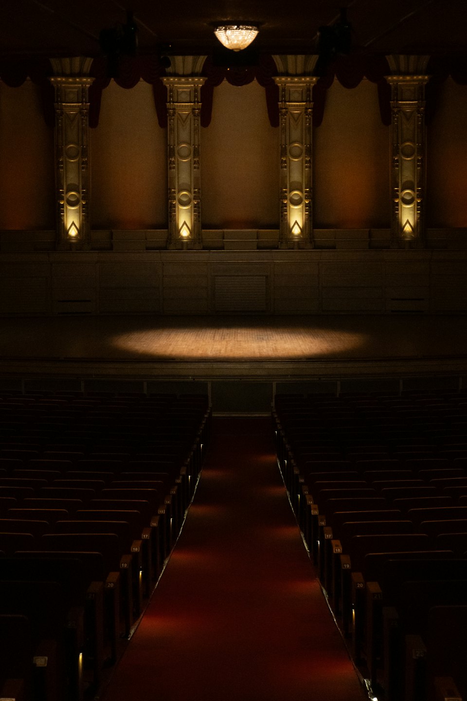 Spotlight on an empty stage in a grand, elegant auditorium.