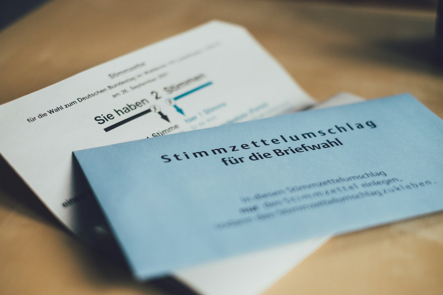Postal ballot envelope and instructions on a wooden table.